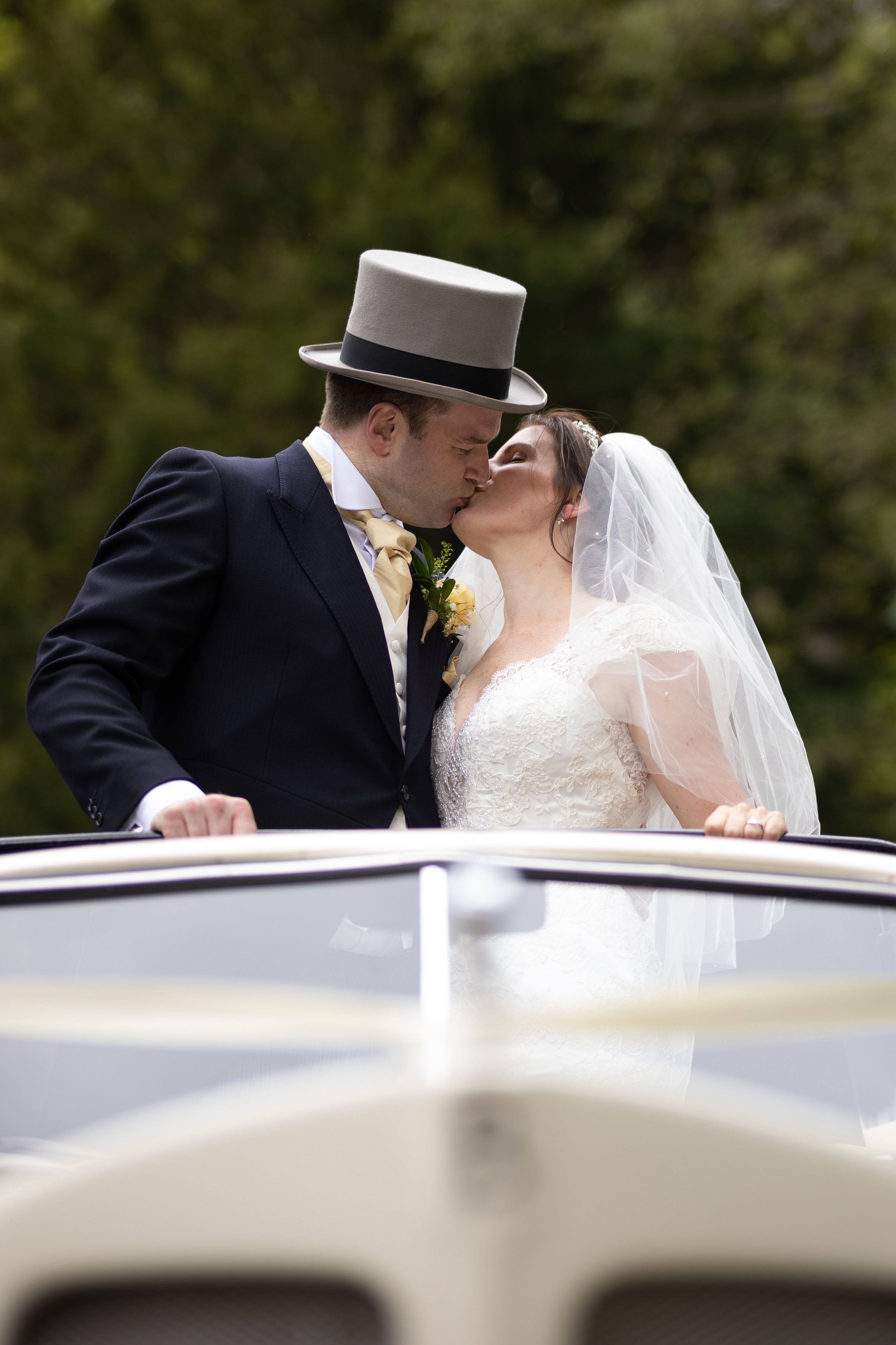 The bride and groom kiss in the wedding car 