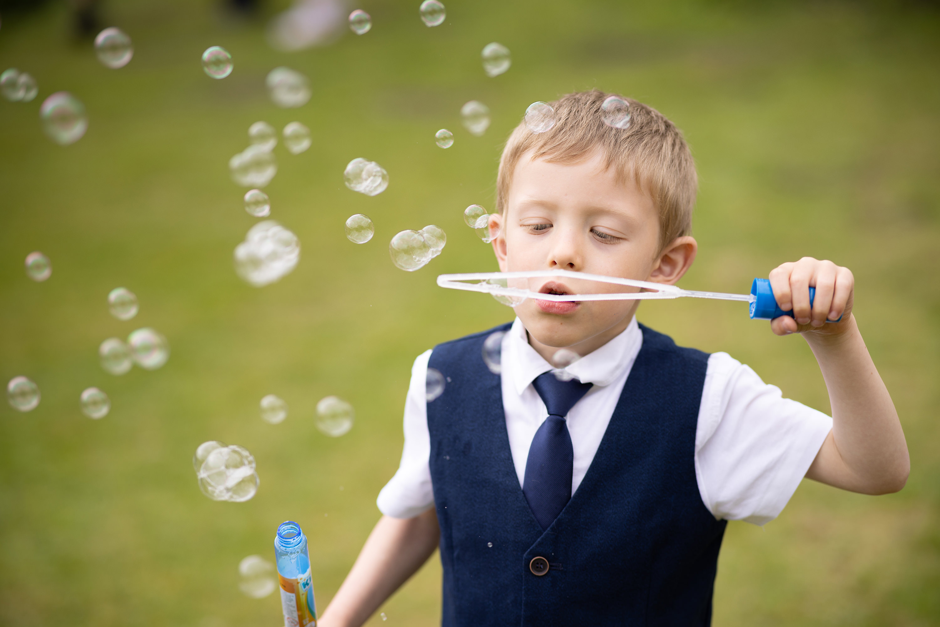 A little boy enjoys playing bubbles at the wedding 