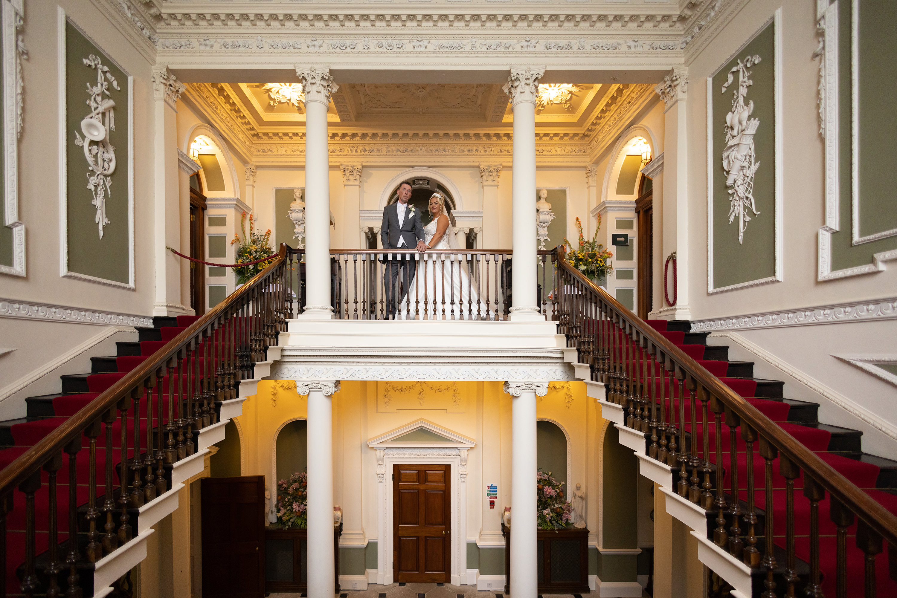 The bride and groom pose for a photo on the staircase