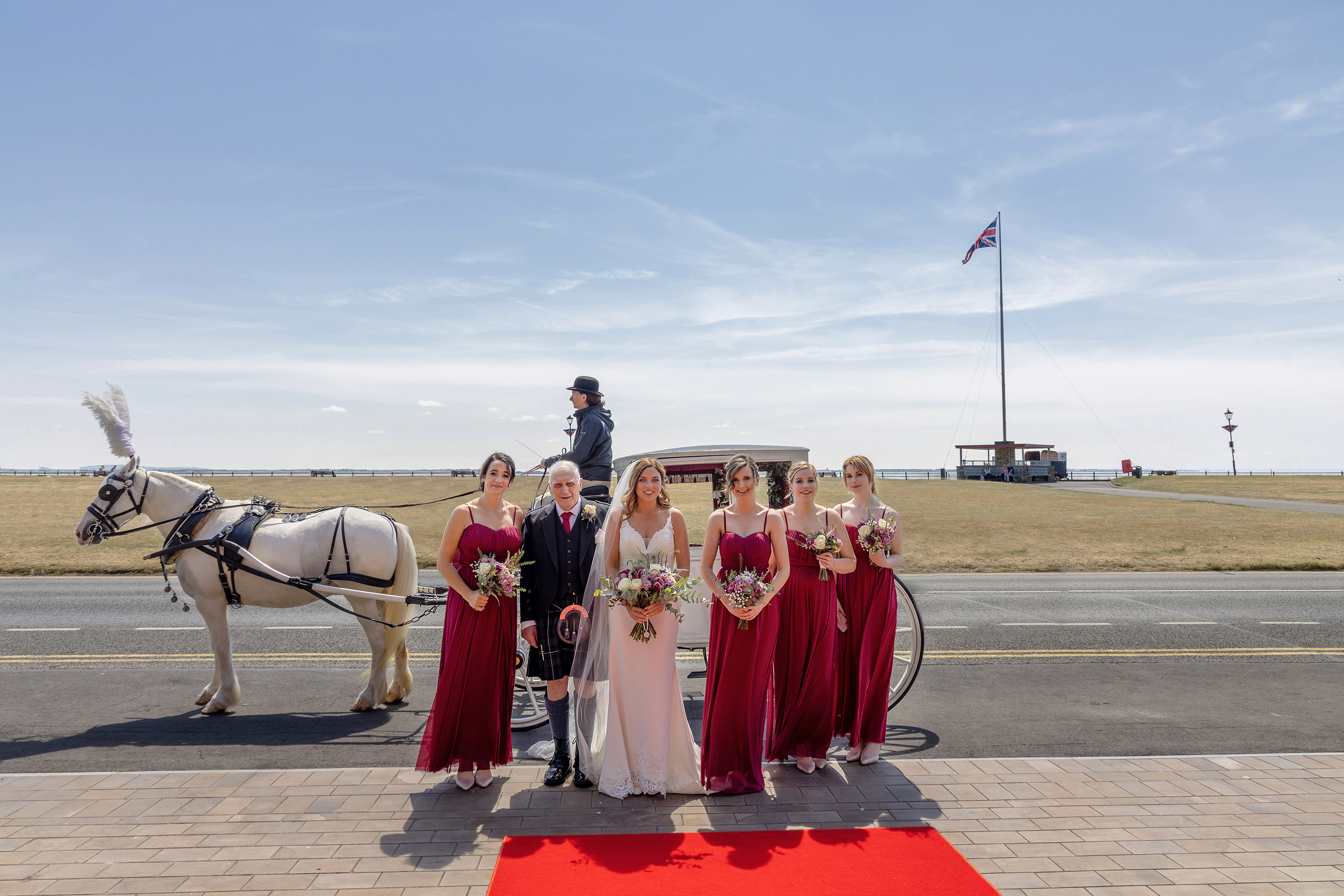 Bridesmaids and bride stand by the horse and carriage on Lytham Green 