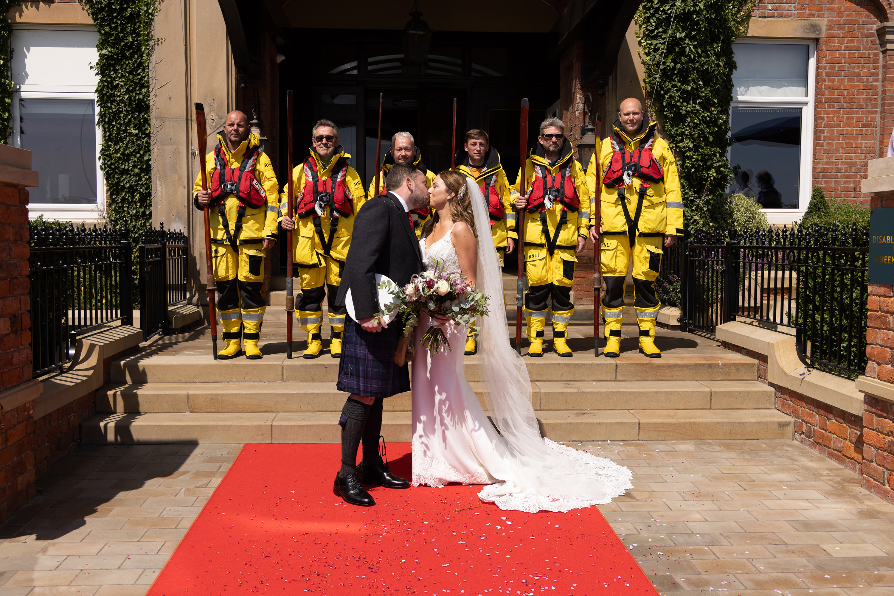 The bride and groom have a kiss with the Lytham Royal lifeboat station men