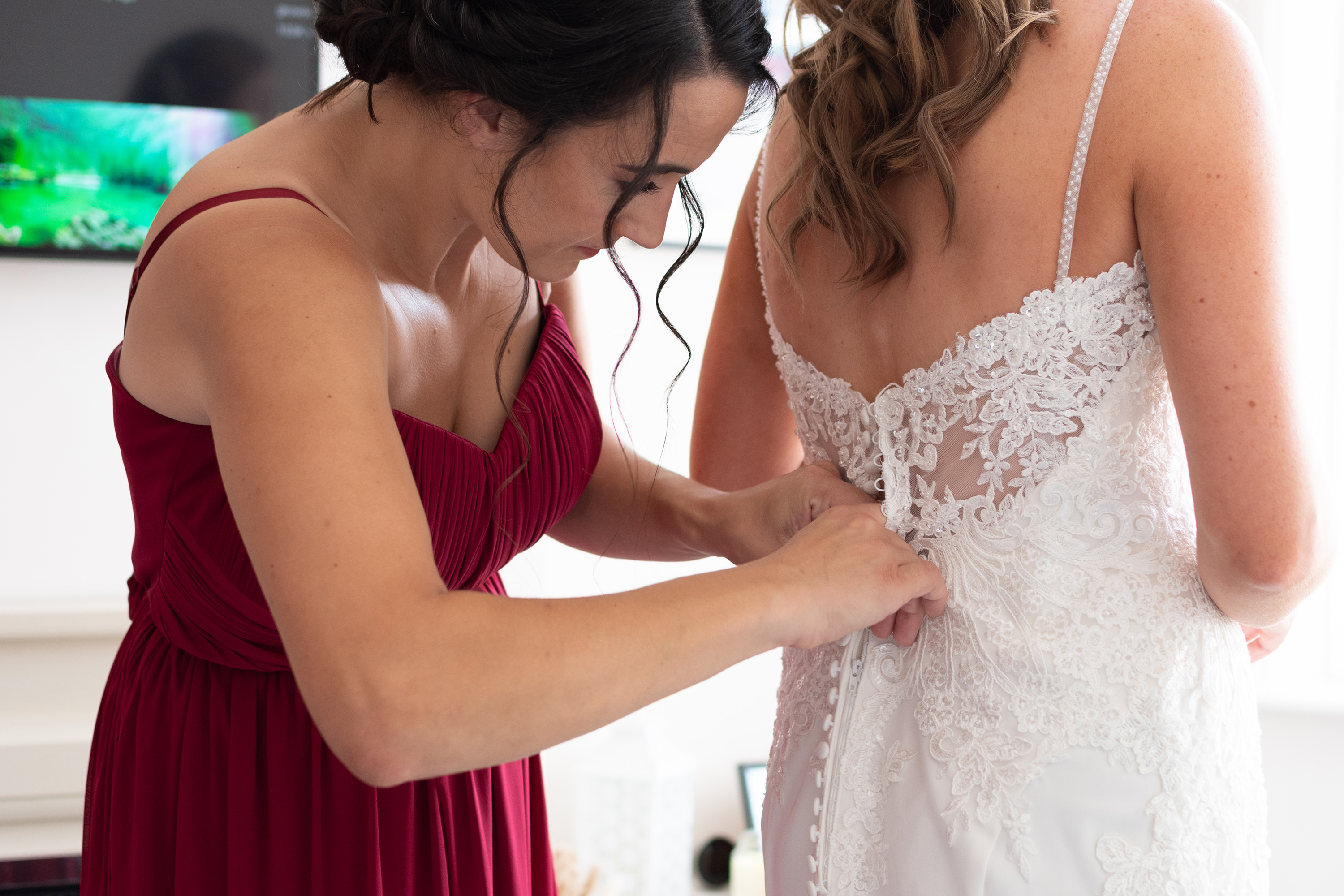 Bridesmaid helping Beverley with her wedding dress 
