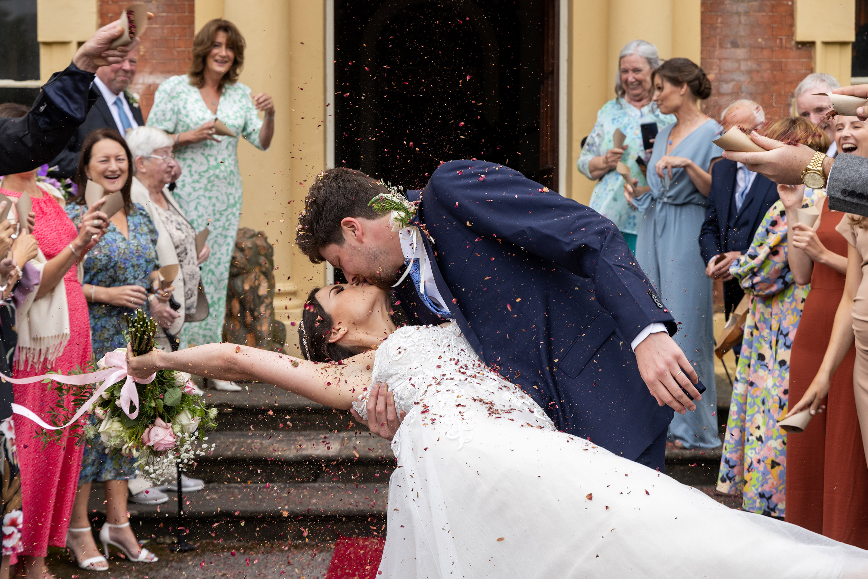 The wedding guests shower confetti over the bride and groom 