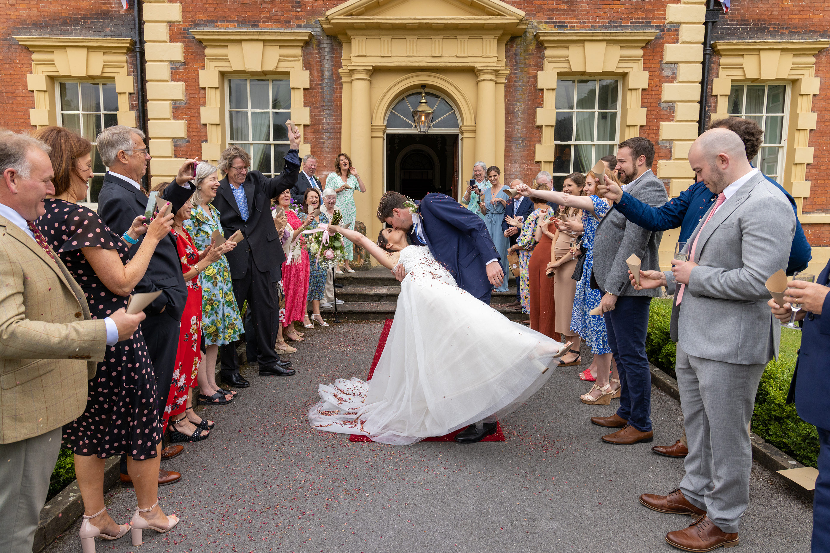 The bride and groom have a kiss under the confetti shower 