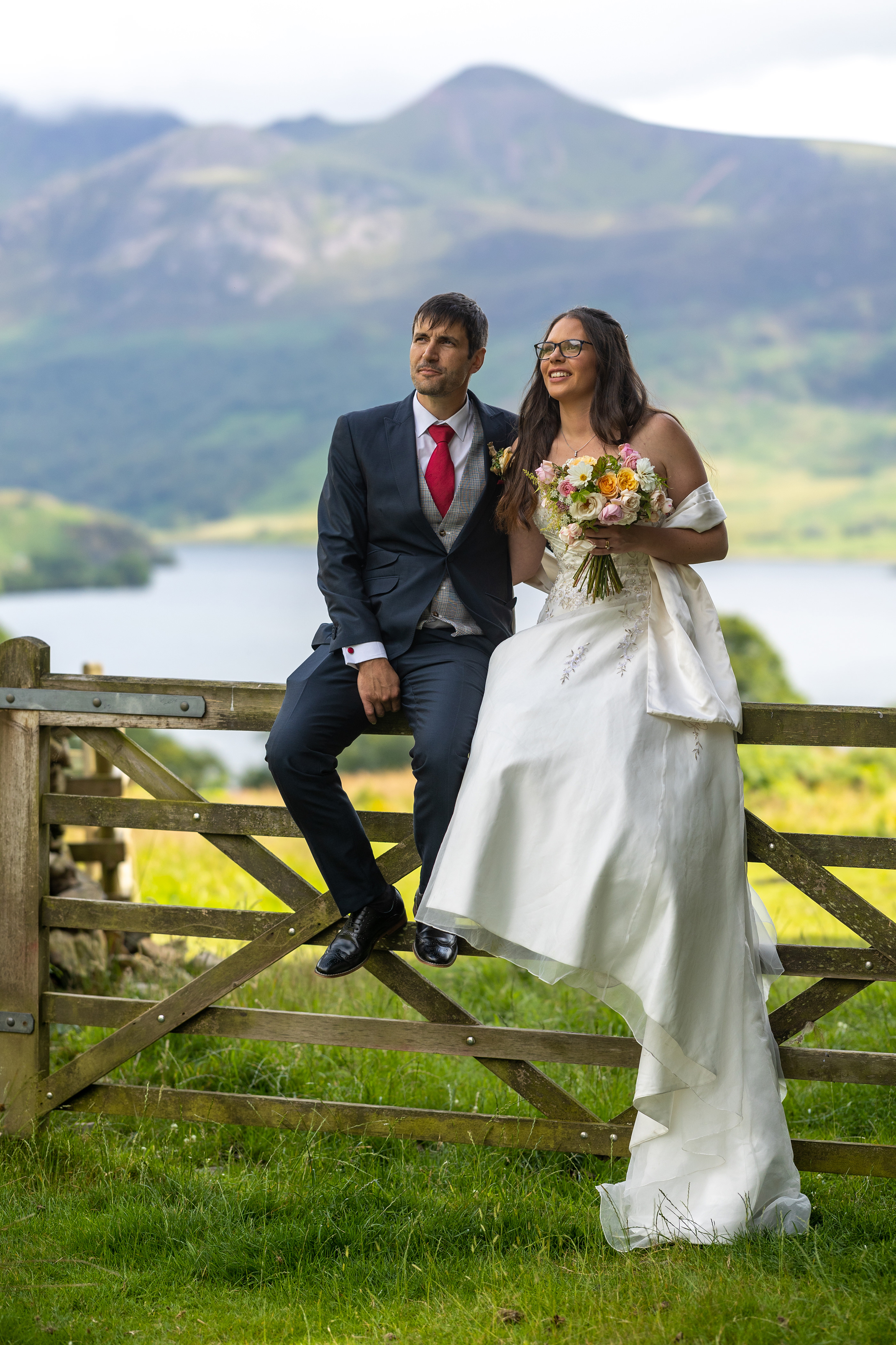 The bride and groom from a fence looking across the countryside 
