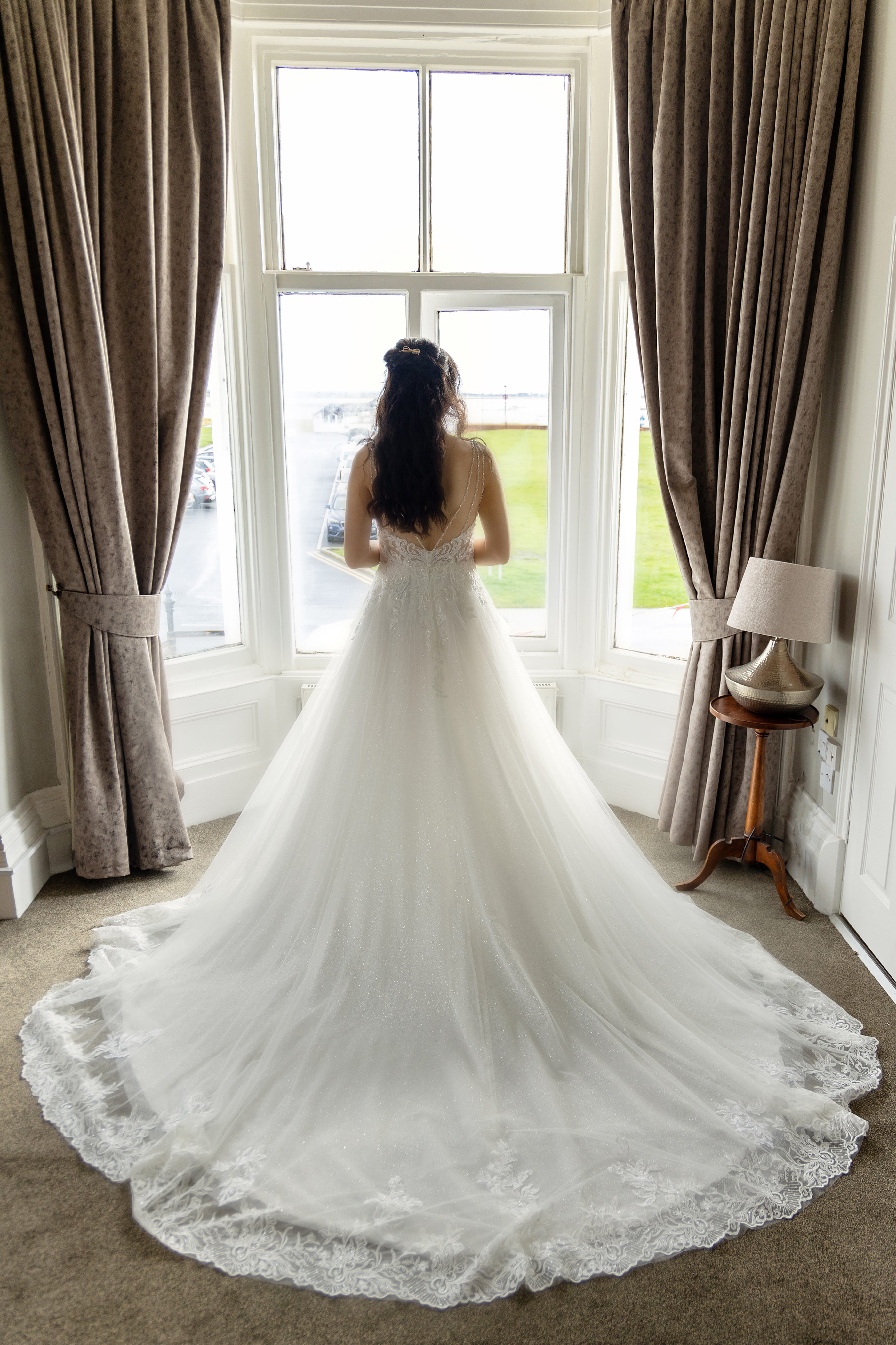 Emily standing in front of the window in her wedding dress 