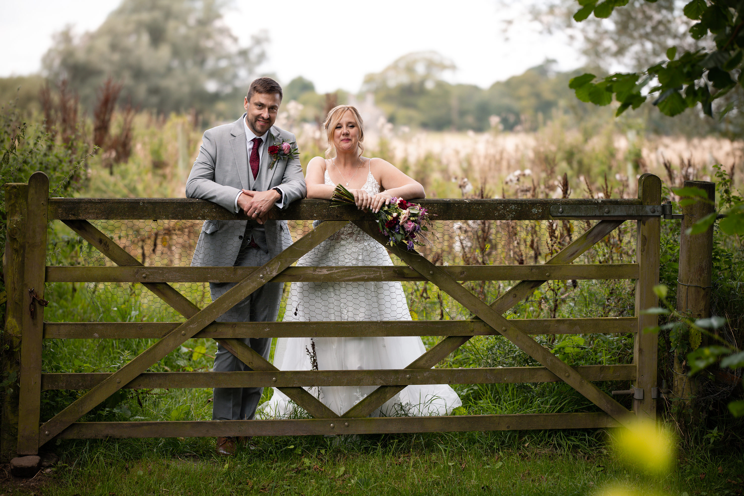 The happy couple stand at a gate in the Yorkshire Dales 