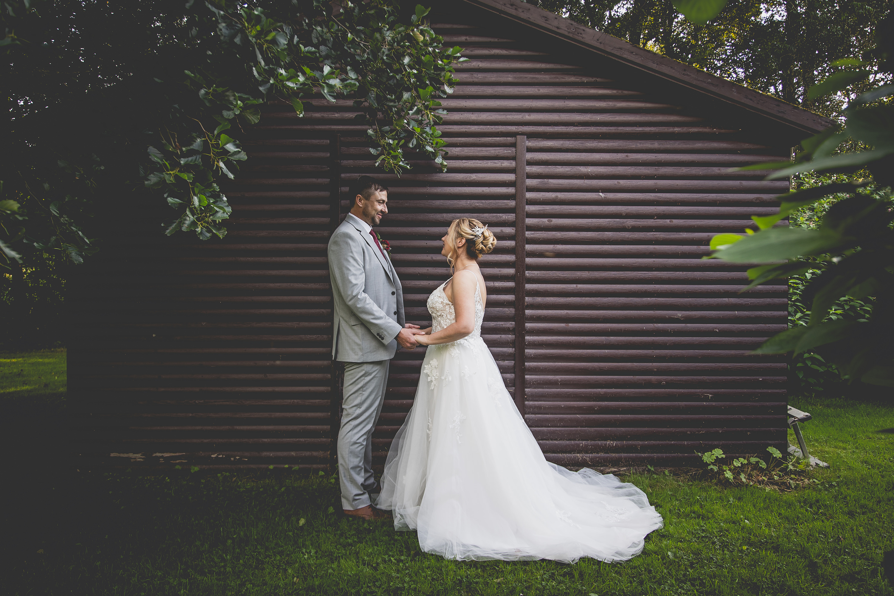 The bride and groom stand  hand in hand at hipping Hall