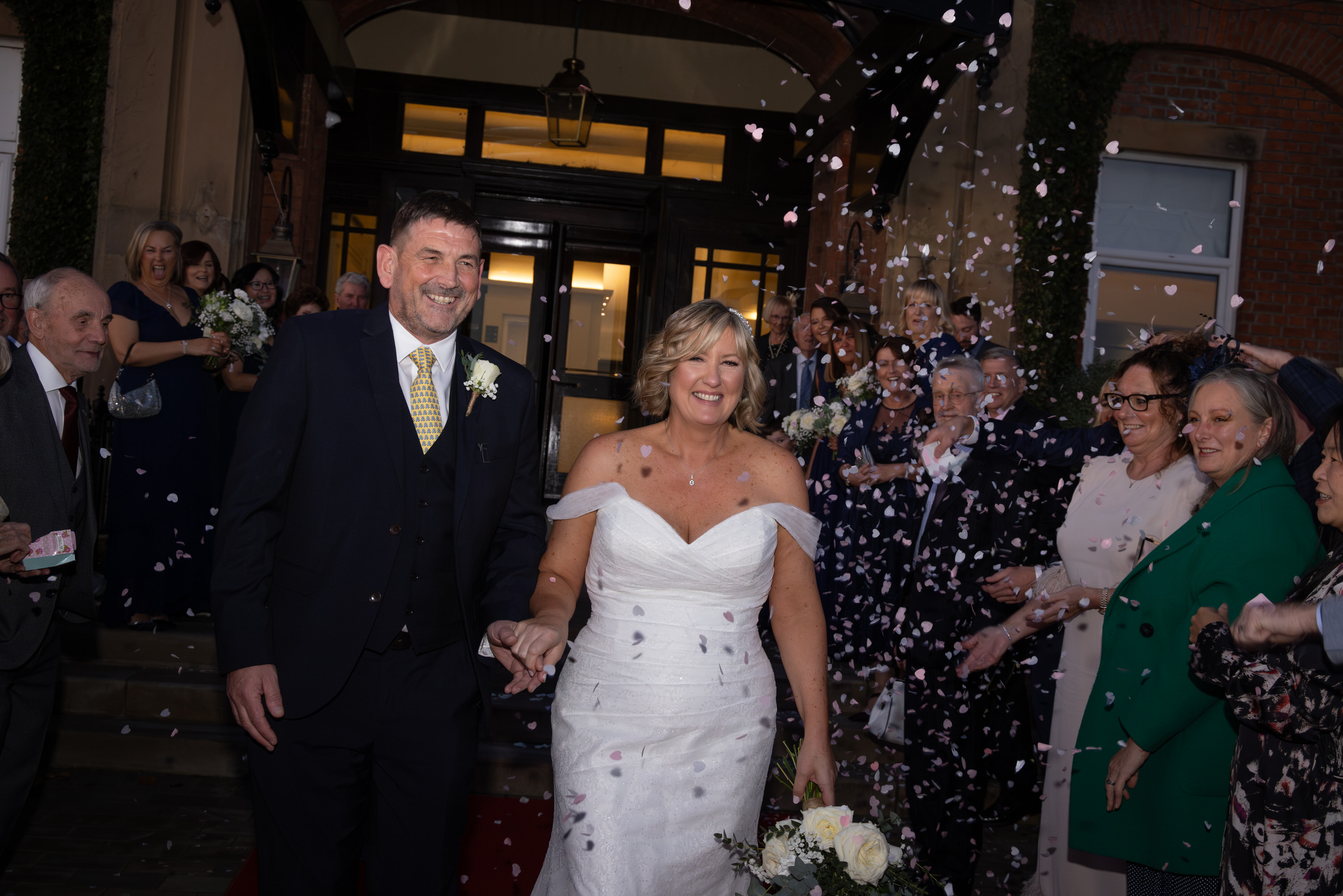 The bride and groom walk through the confetti 