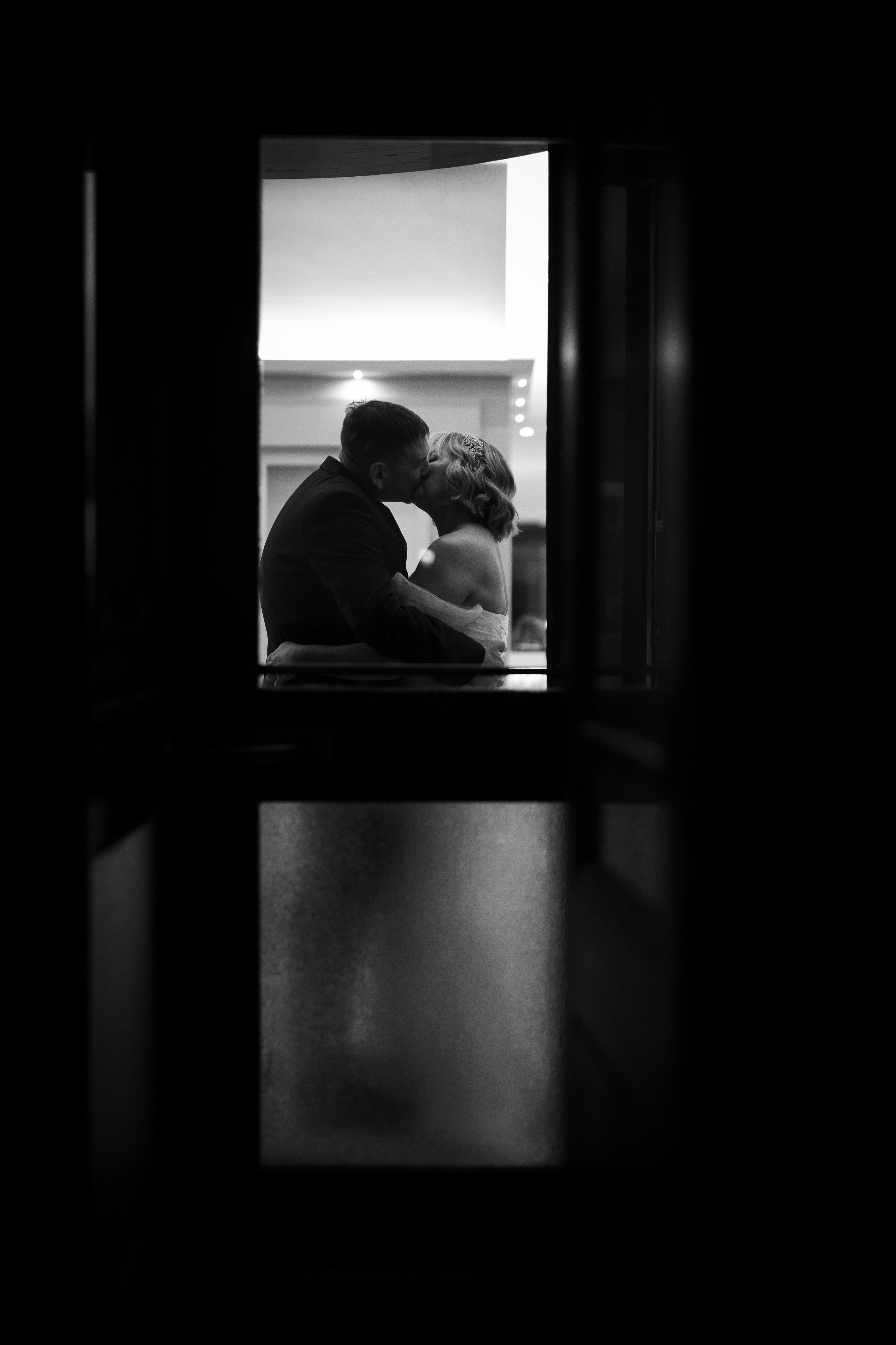 The bride and  groom have a kiss in the doorway