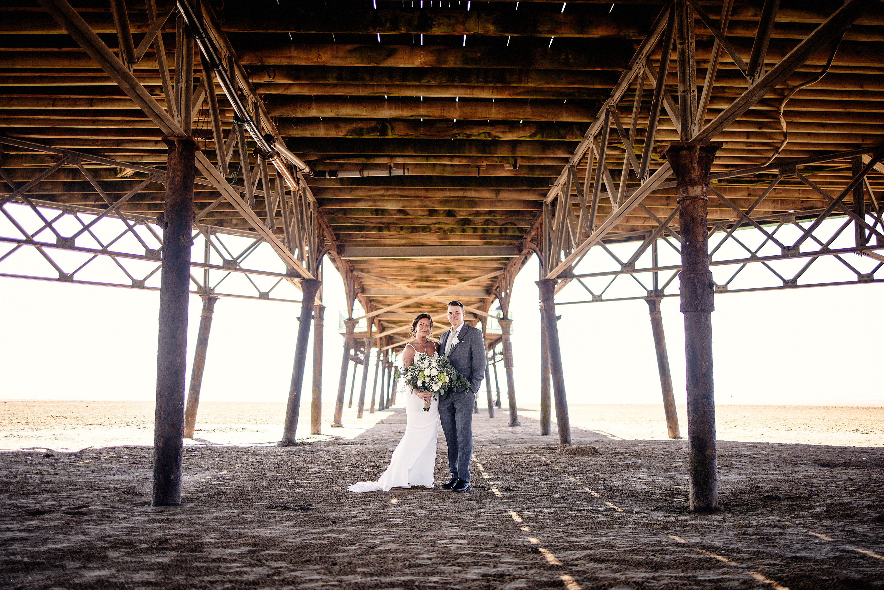 The bride and groom standing underneath St Anne's peer