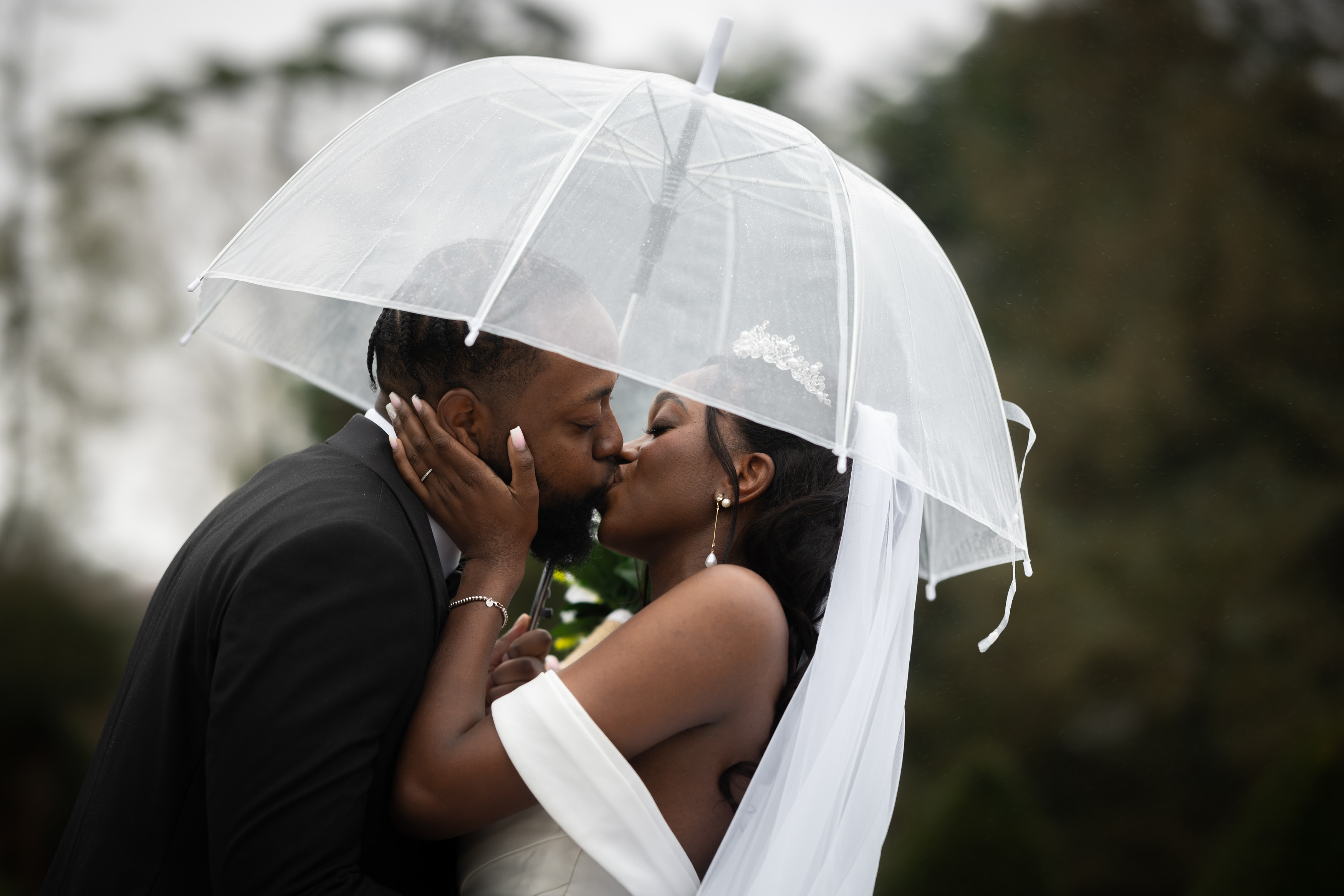 The bride and groom have a kiss in the rain 