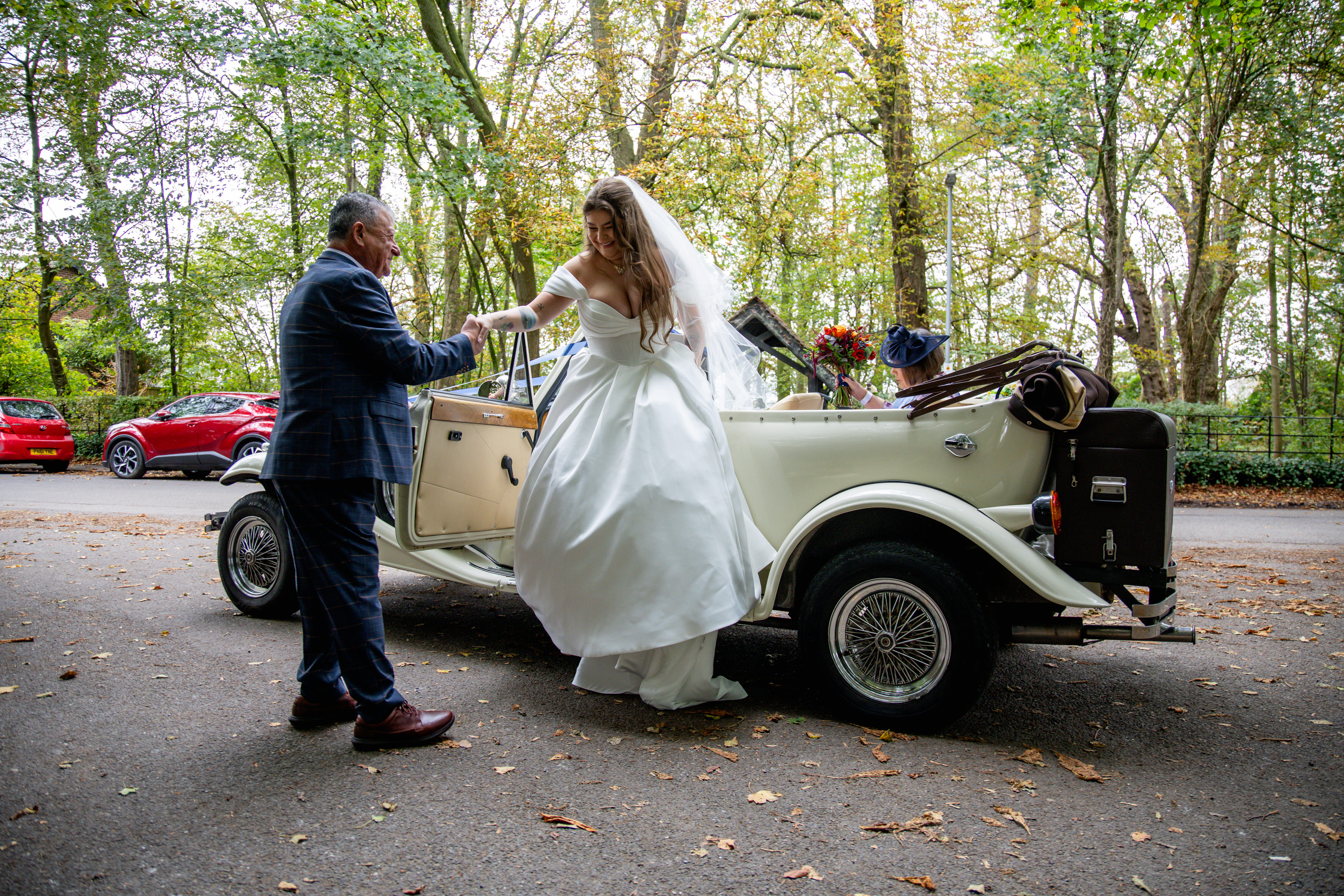 The bride's father helps his daughter out of the car 
