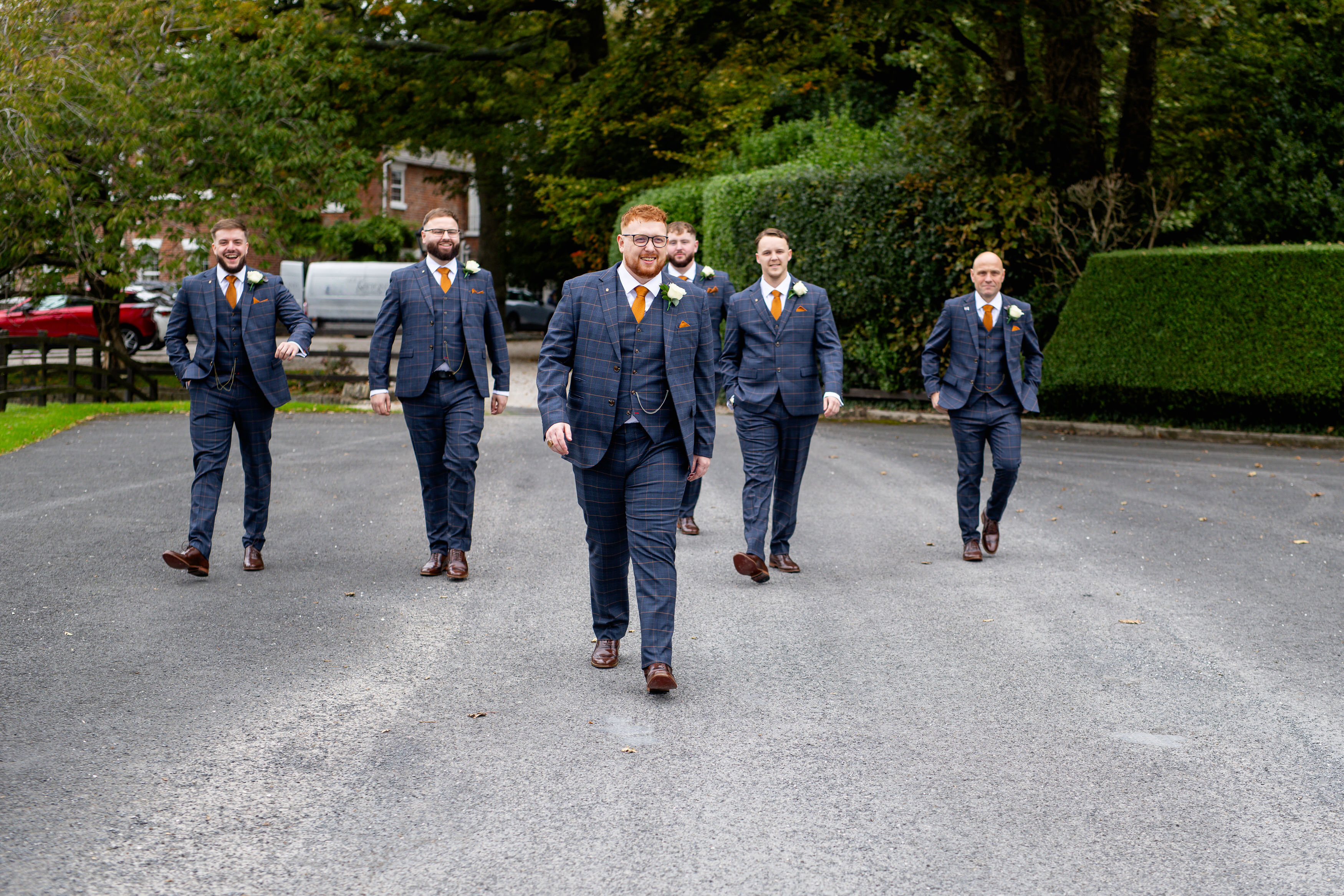 The groom and his groomsmen walking down the drive 