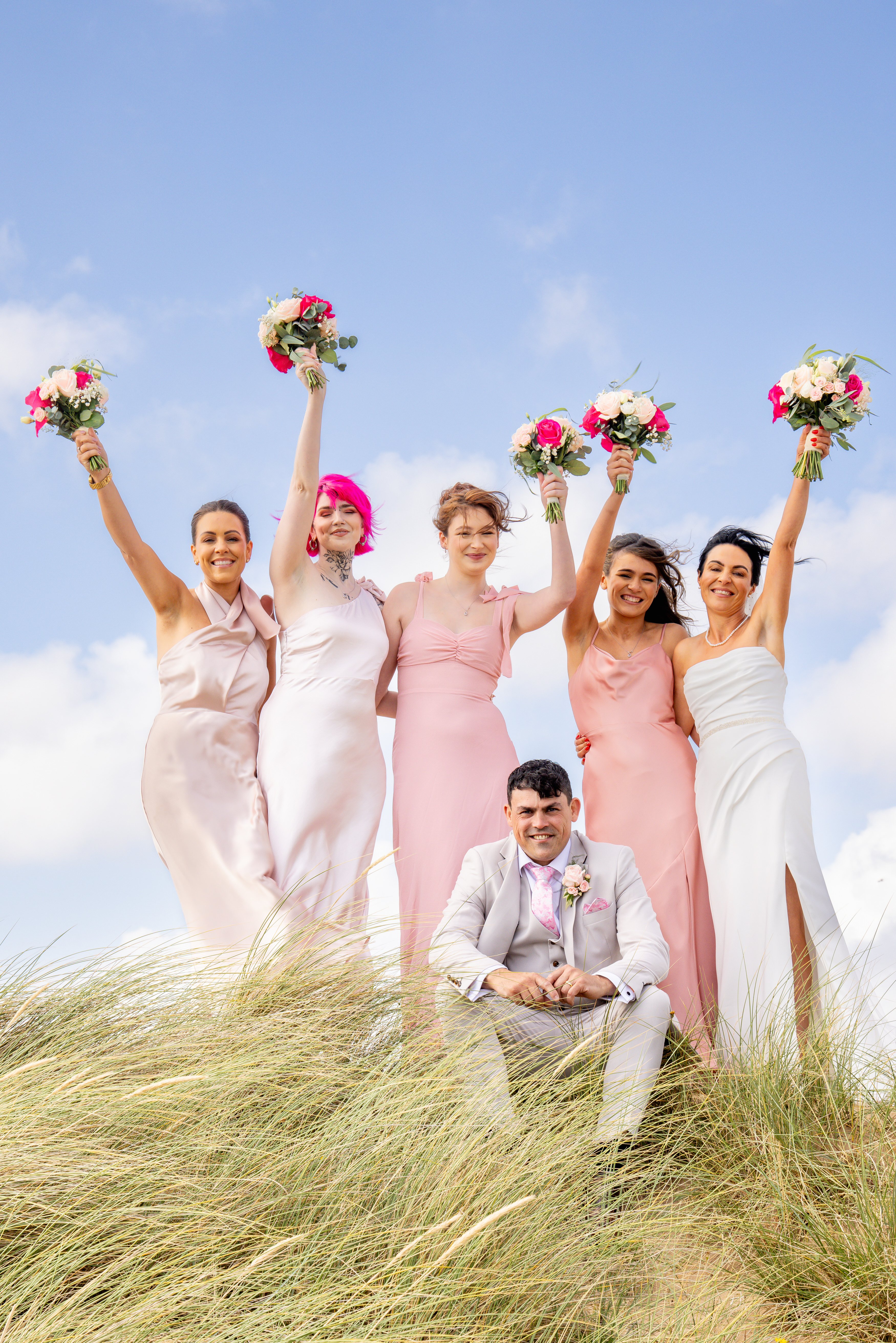 The bride and bridesmaids raise their bouquets in the air 