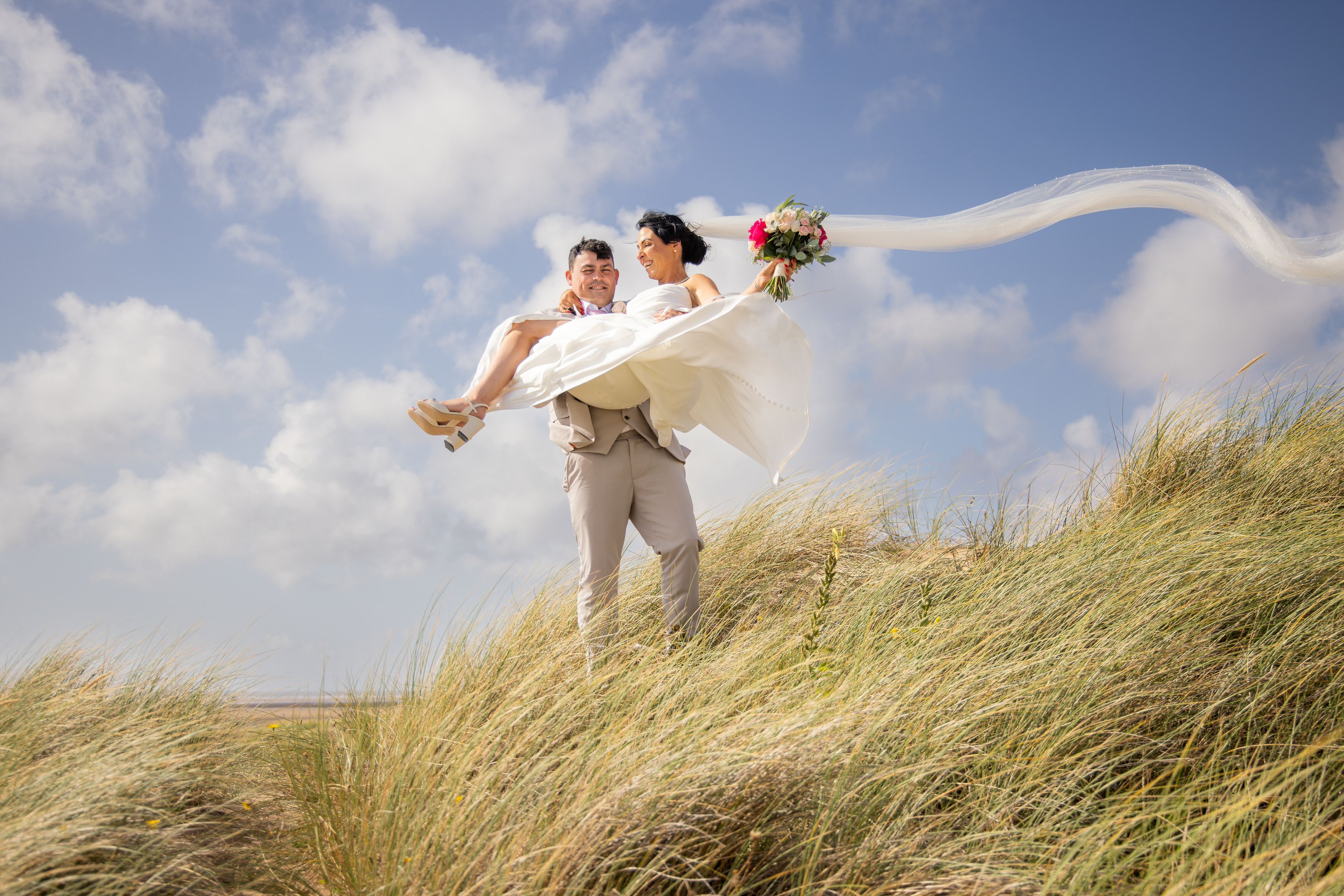 Andrew carriers his bride Sarah down the sand dunes