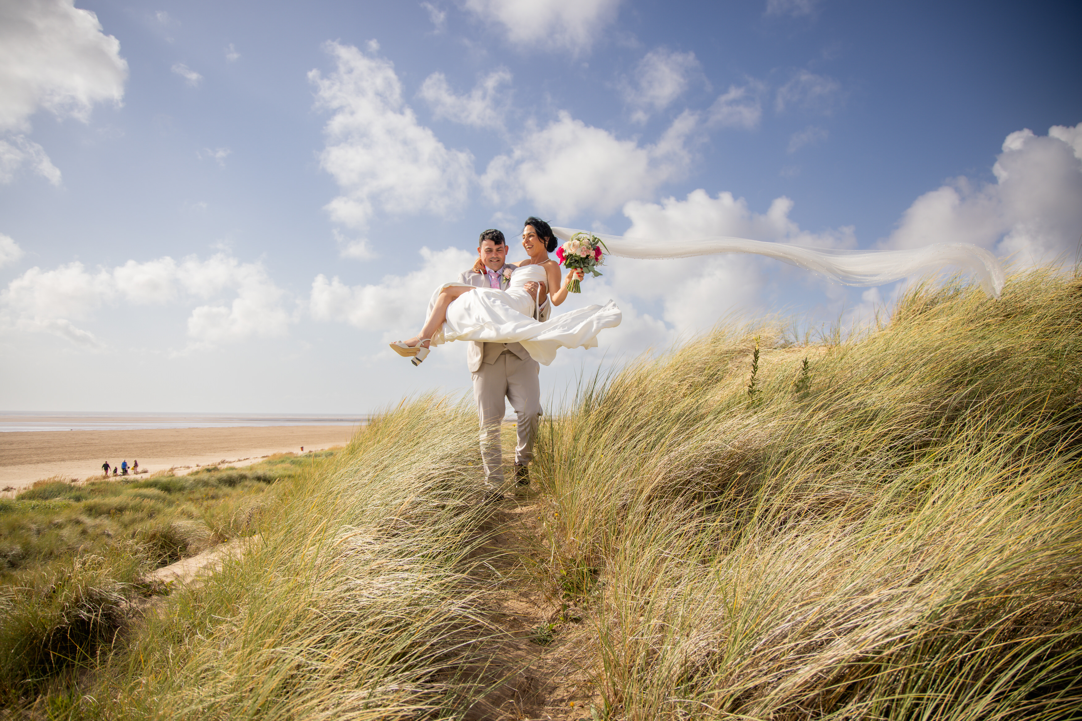 Andrew carriers his bride Sarah down the sand dunes