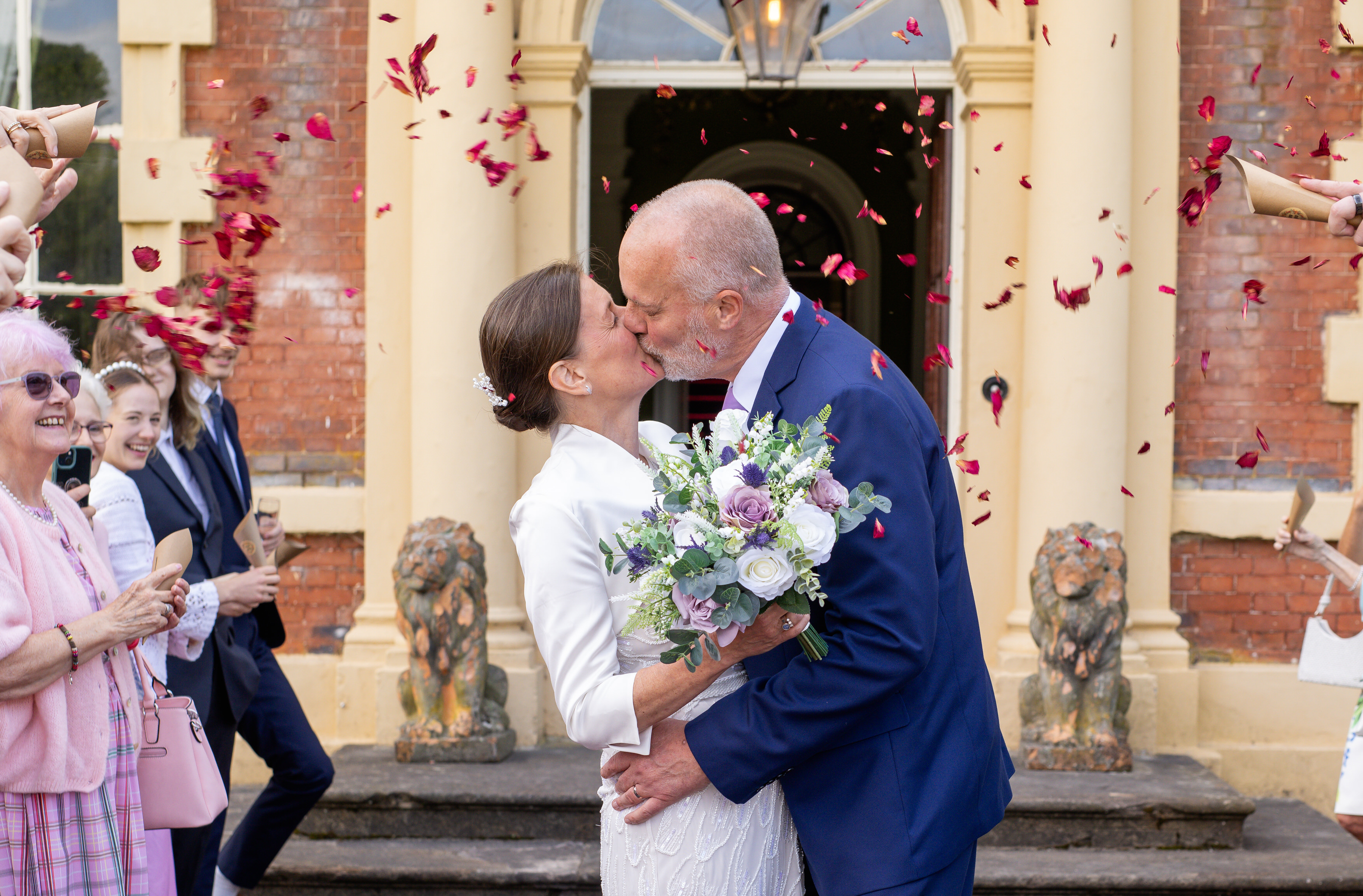 The wedding guests throw confetti at the bride and groom as they leave lytham Hall