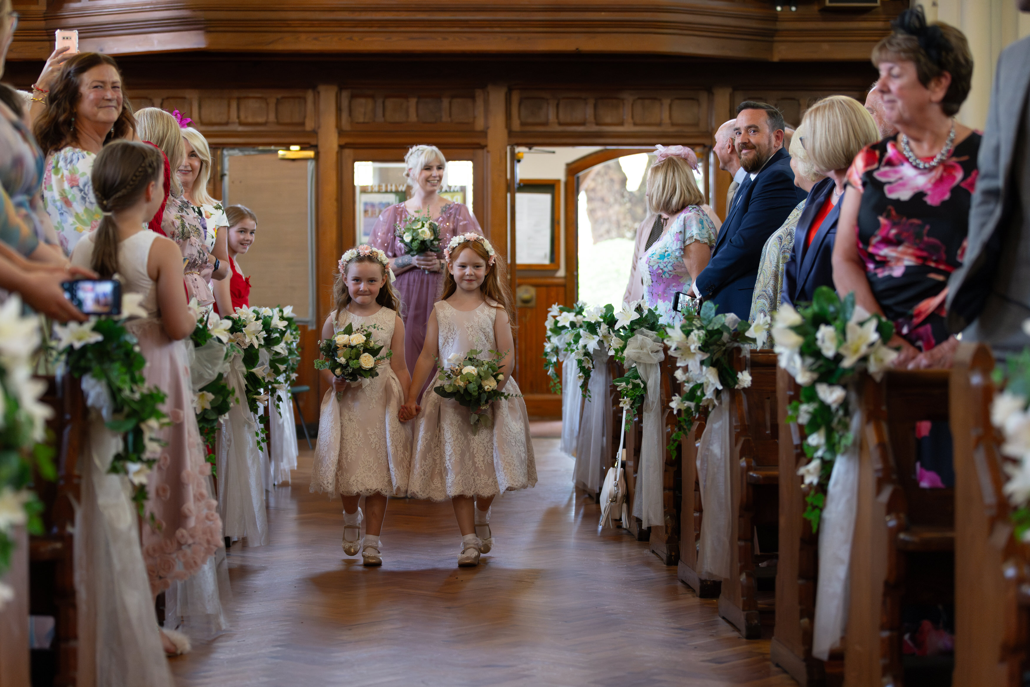 The flower girls walk down the aisle in the church 