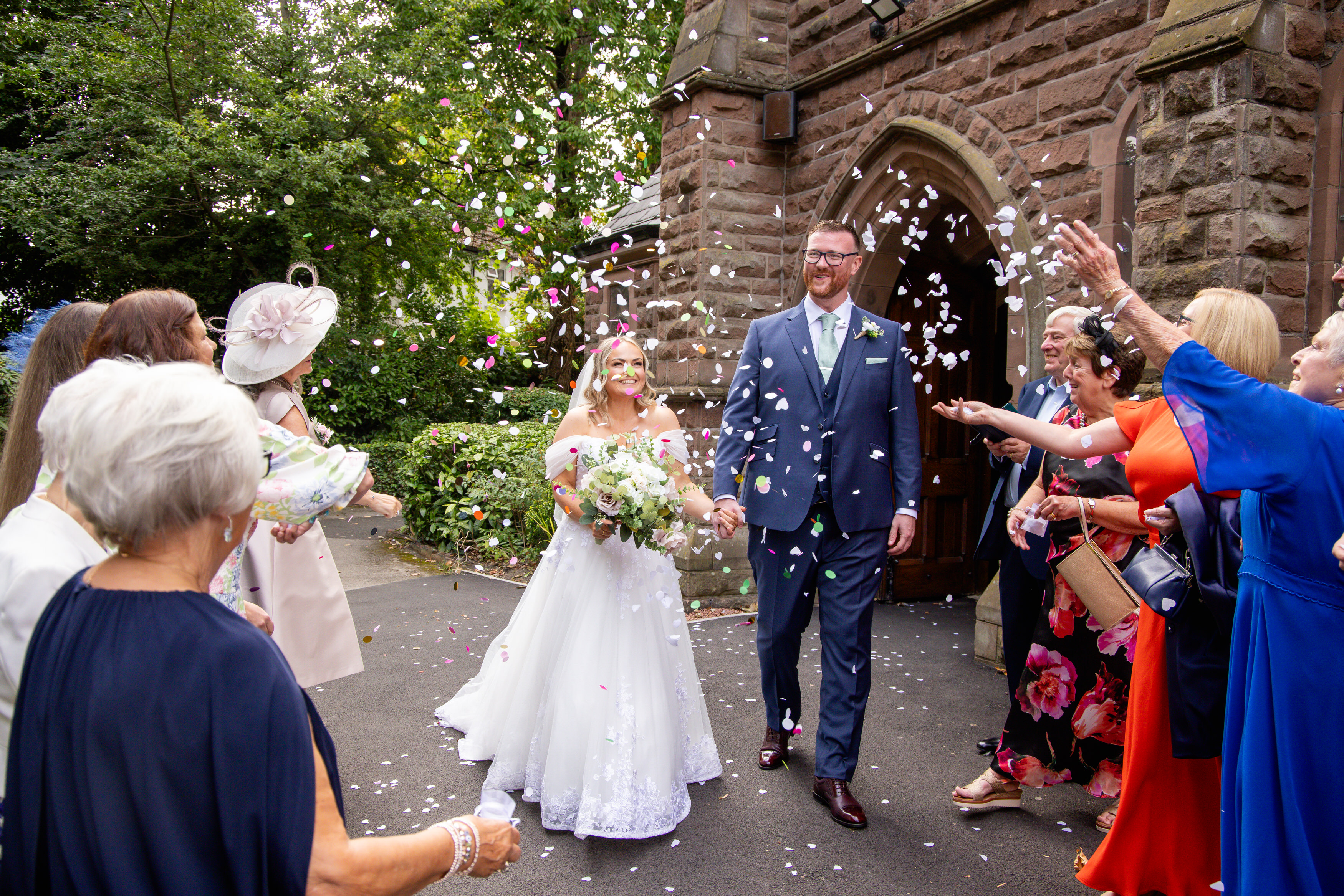 The wedding guests through confetti at the bride and groom 