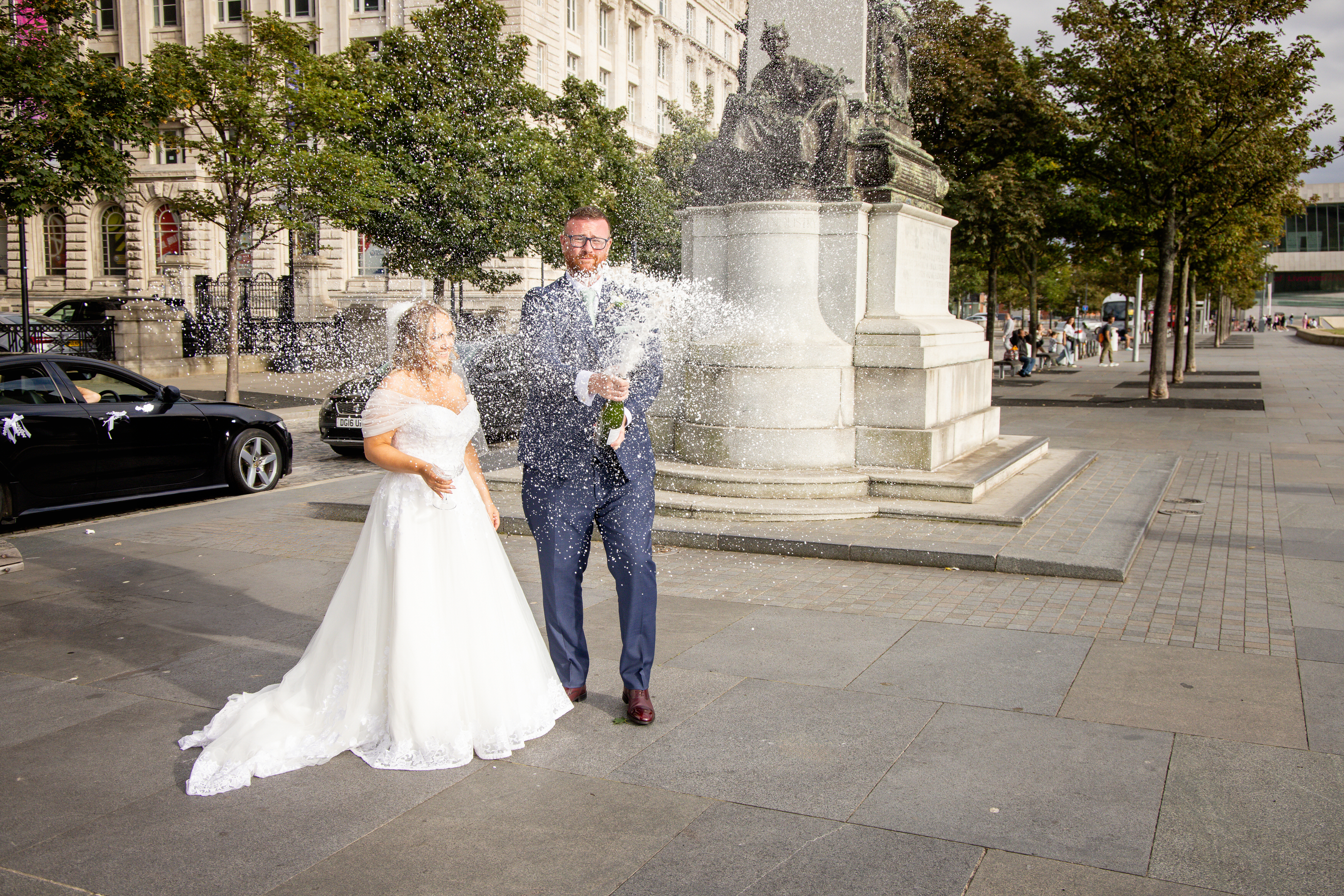 The bride and groom opened a bottle of champagne outside the Liver buildings in Liverpool 