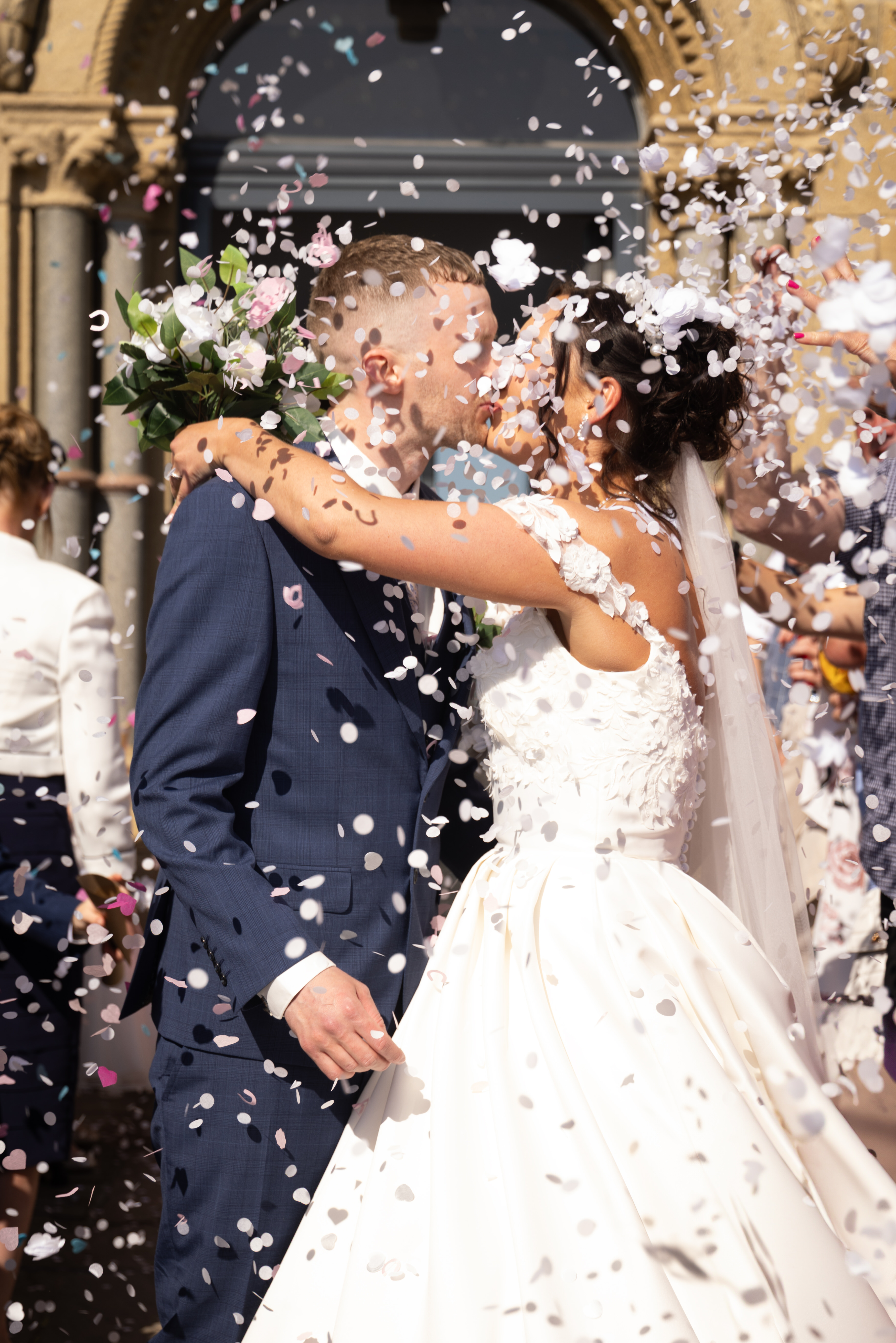 The wedding guests throw confetti at the happy couple 