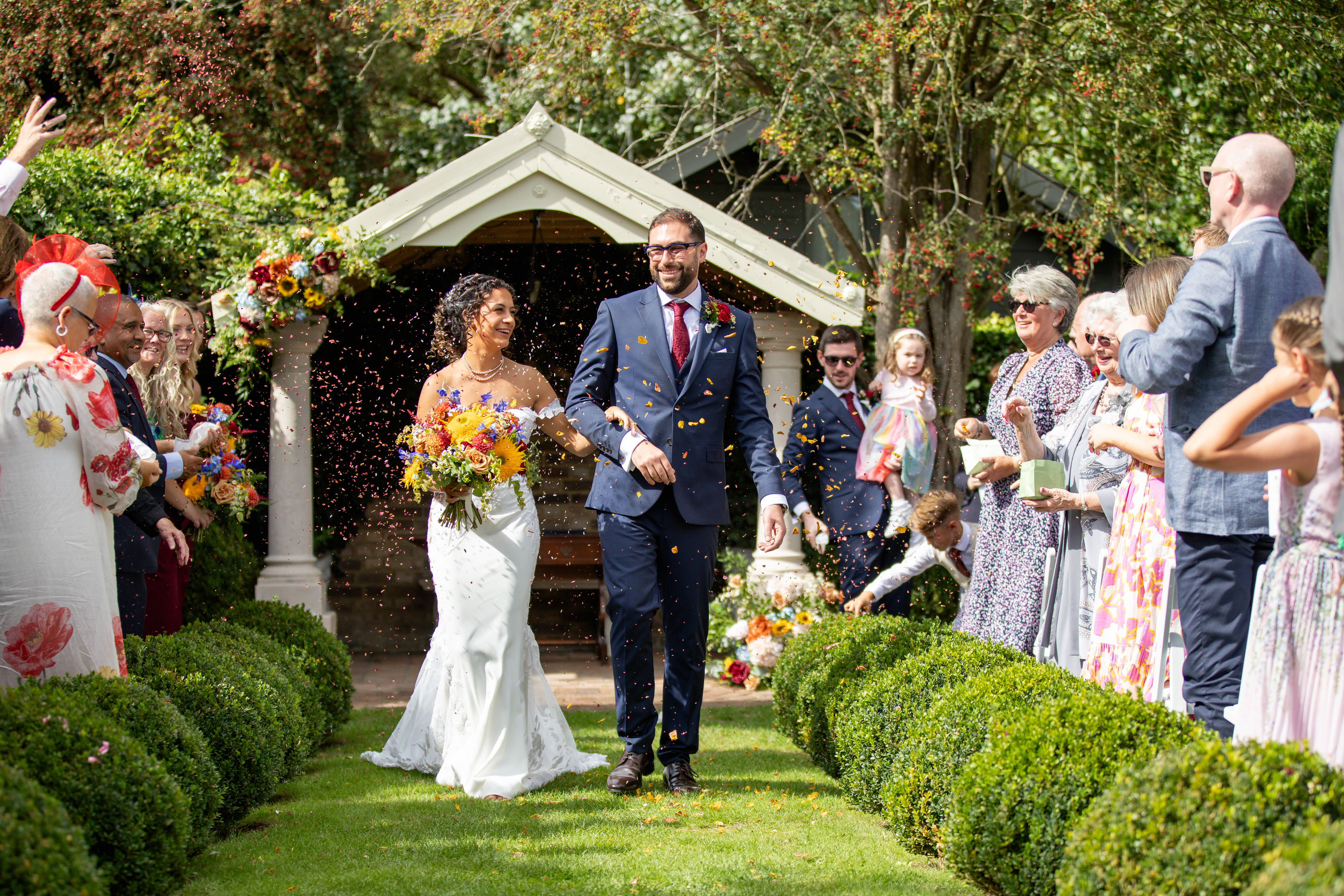 The bride and groom walk down the isle as people throw confetti