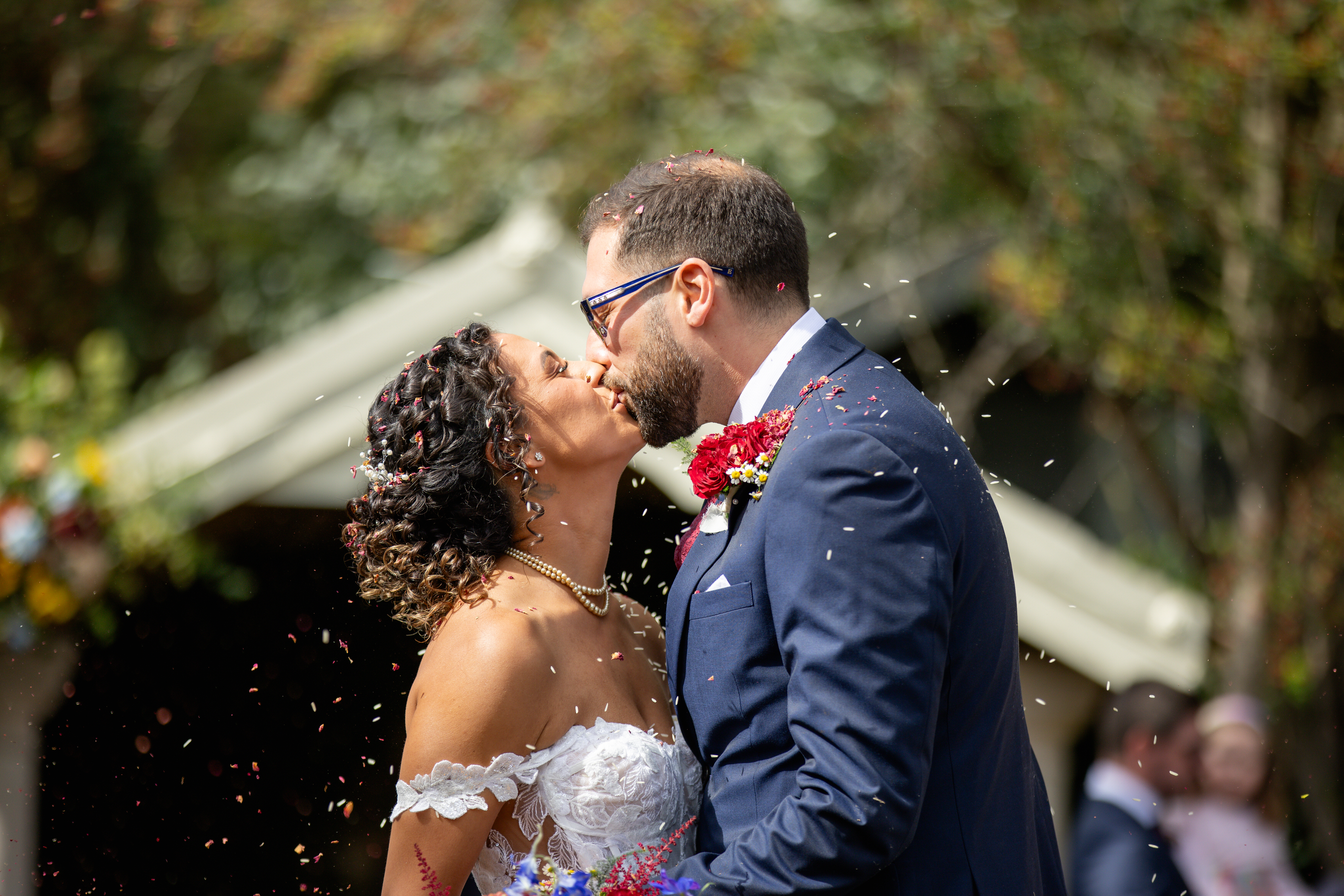 The bride and groom walk down the isle as people throw confetti