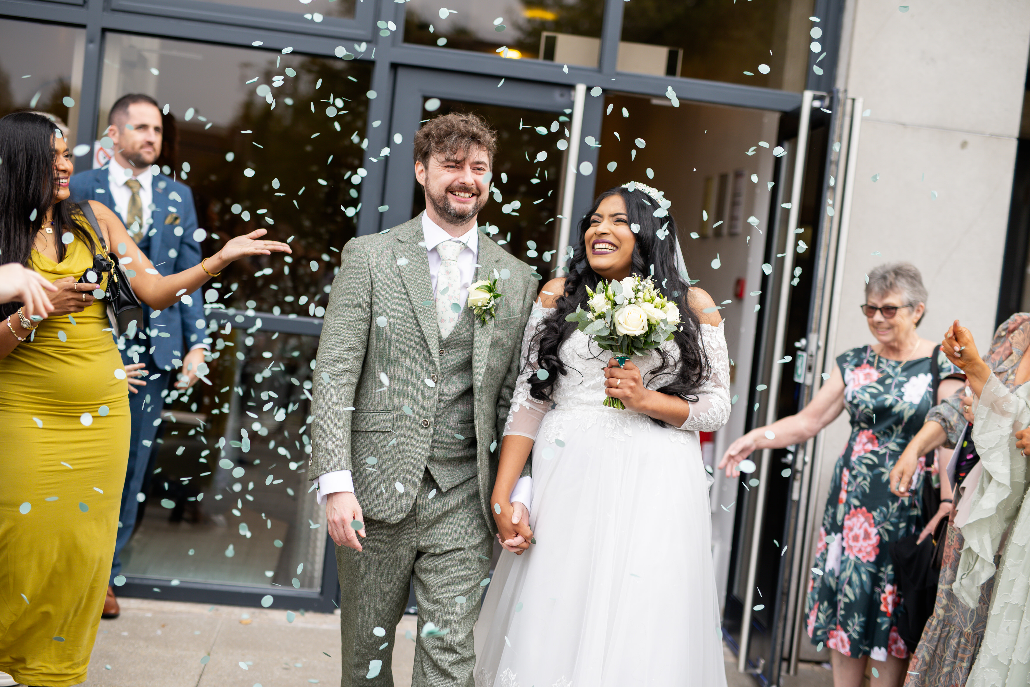The wedding guests throw confetti over the happy couple 